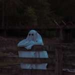 person in white hoodie sitting on brown wooden bench