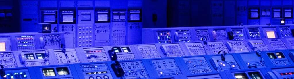 Sala de controle moderna com múltiplas telas exibindo dados e painéis de monitoramento em tempo real